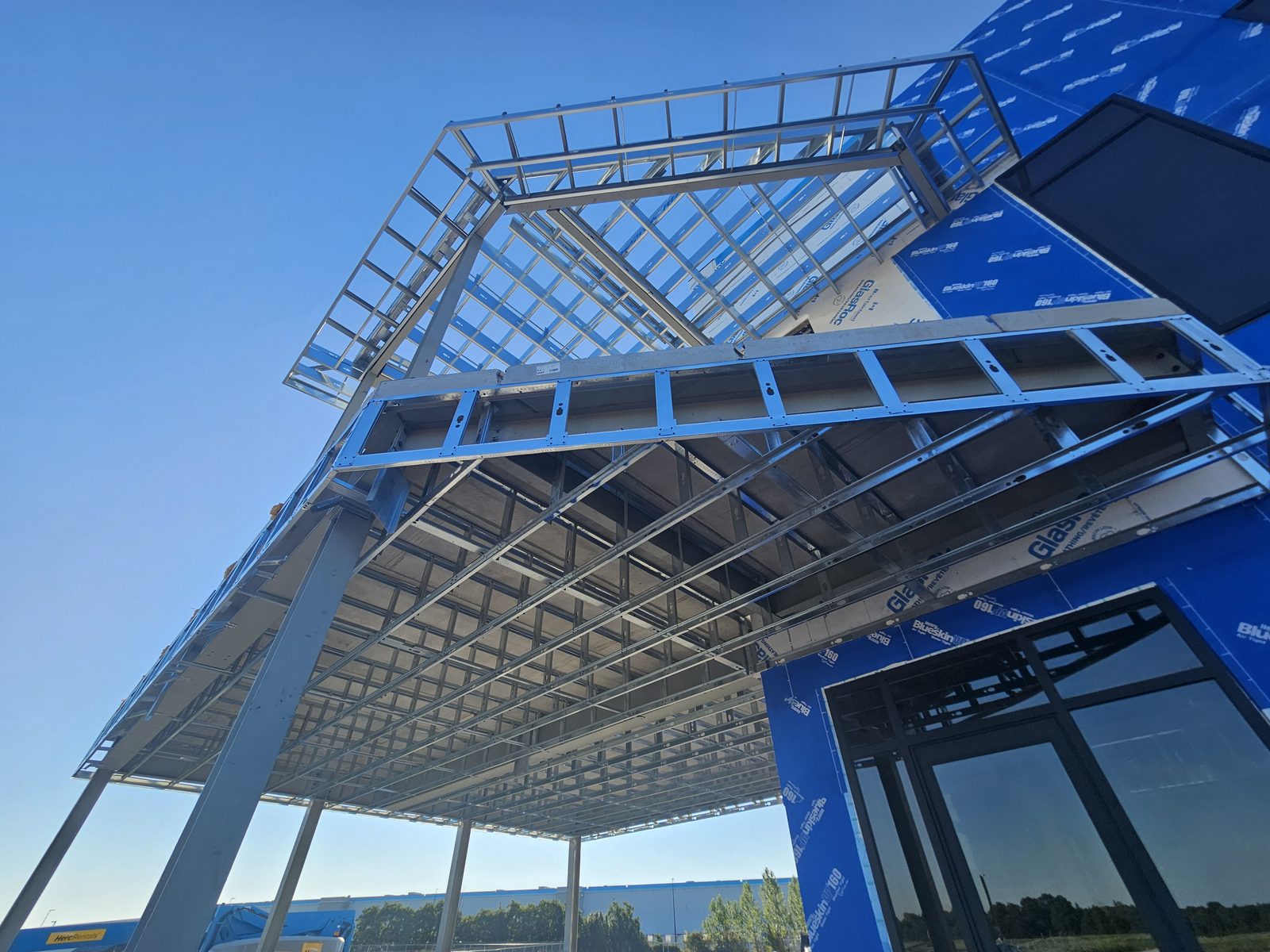 Heavy gauge steel exterior framing on a commercial building under construction, with exterior sheathing partially installed