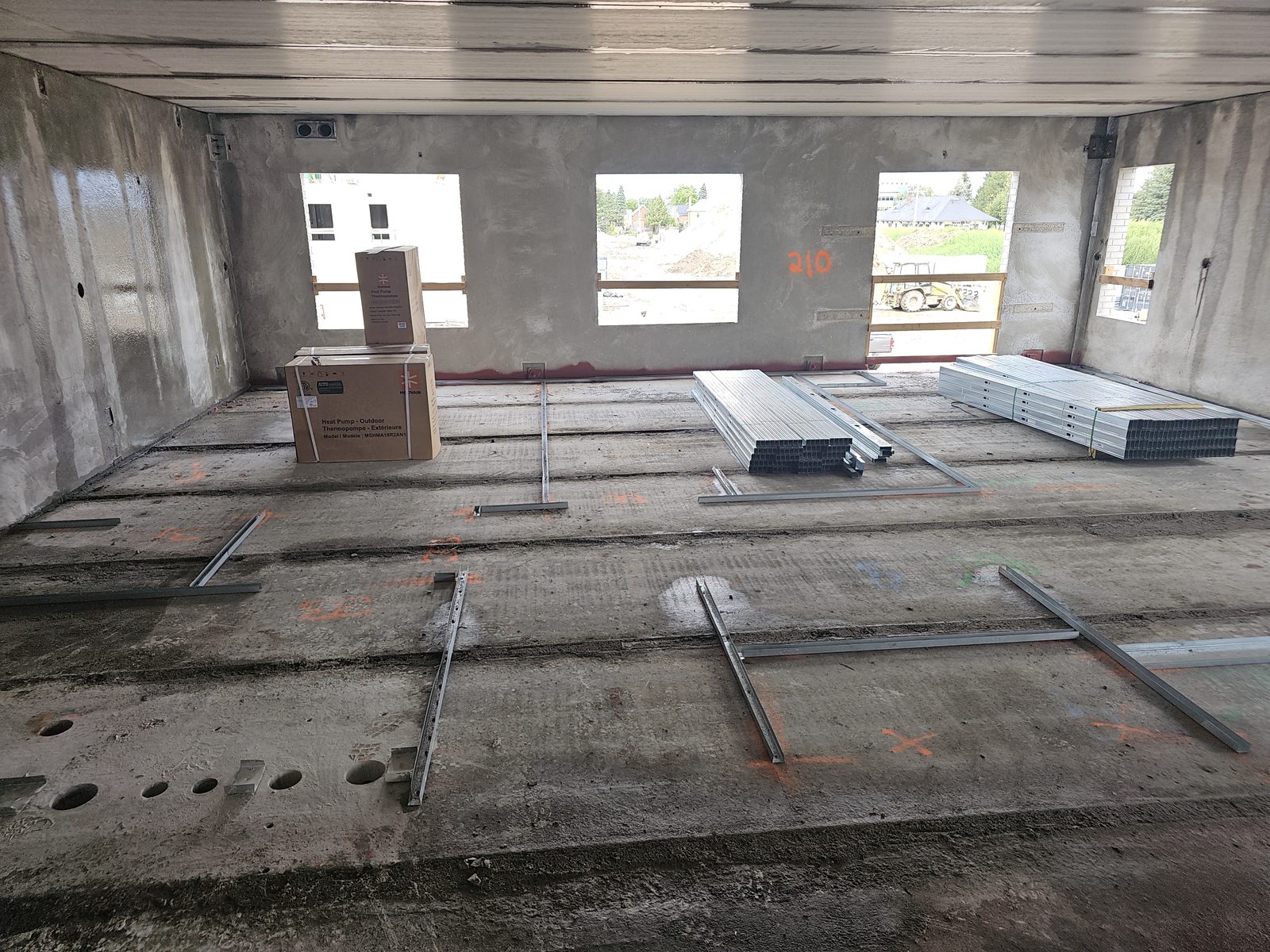 Interior of a high-rise unit under construction in Owen Sound, with metal stud track laid out on the concrete floor for wall framing