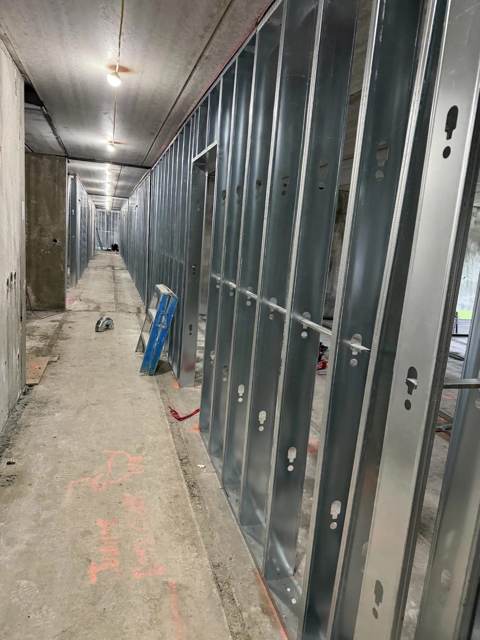 Interior corridor of a building under construction with a long run of metal stud wall framing installed along one side