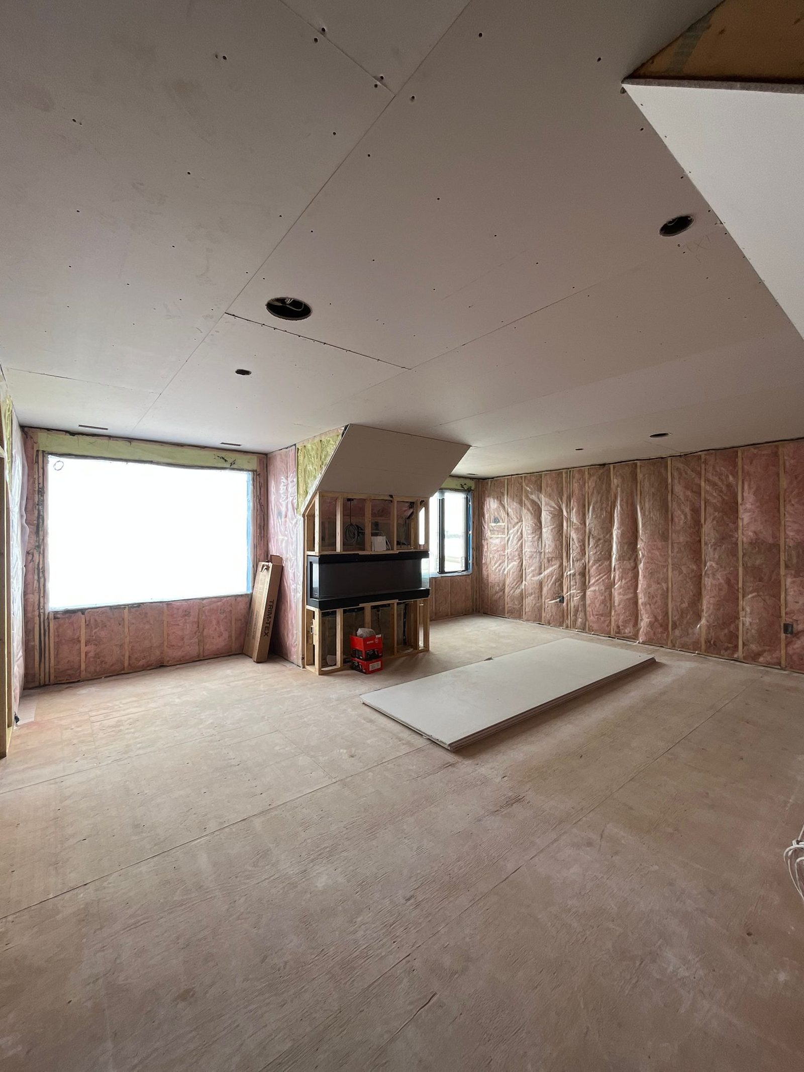 Custom home bonus room with insulation installed on the walls and drywall installed on the ceiling, ready for wall board
